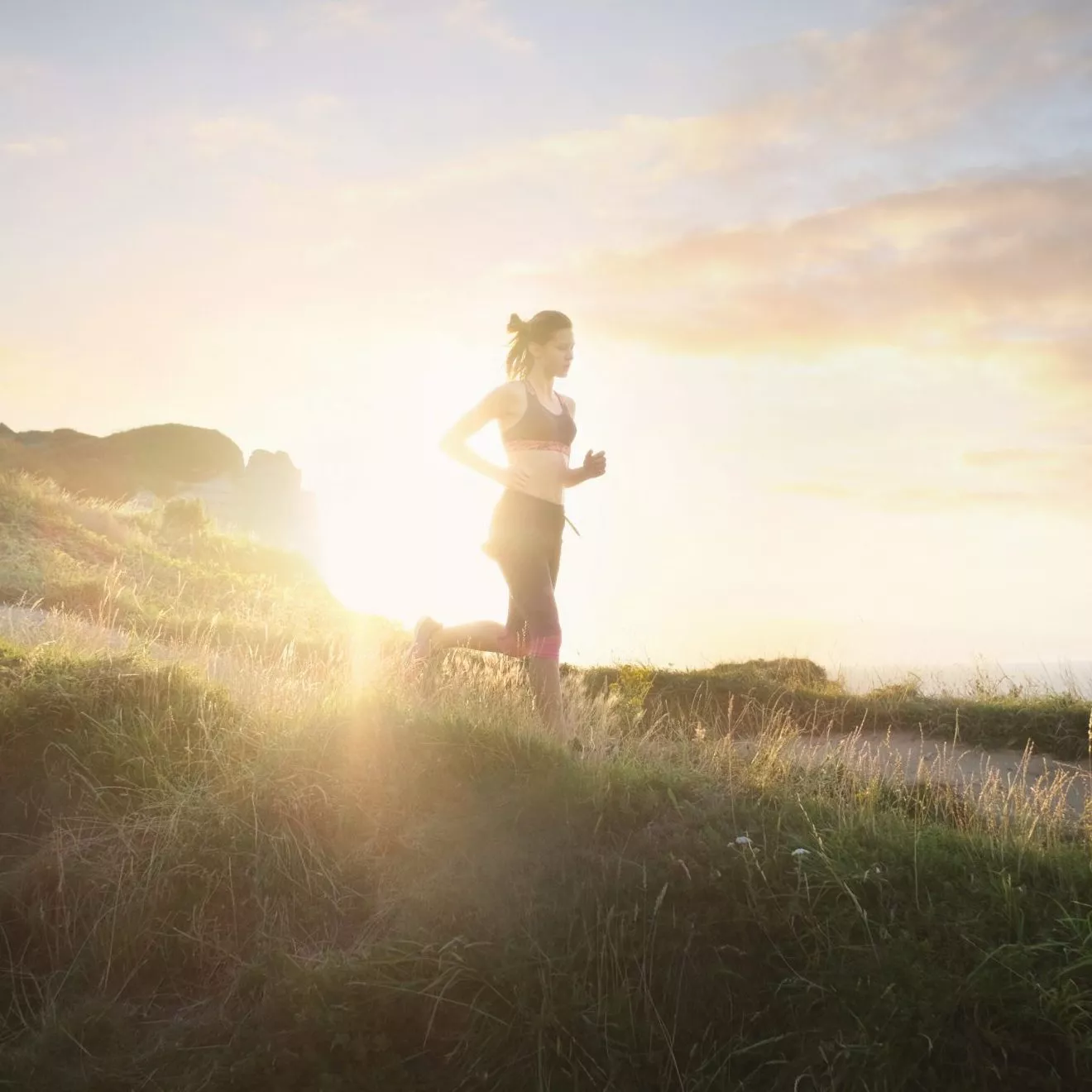 Young woman running near ocean as part of workout motivation